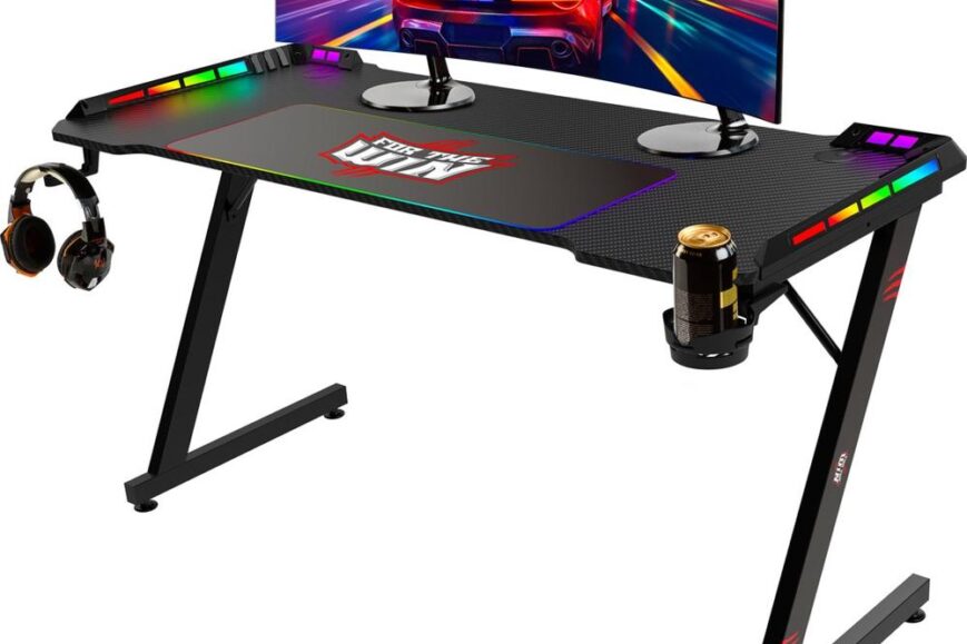 Moderne gamingdesk met een zwart oppervlak, verlichte randen en een groot gebogen computerscherm met een racegame-achtergrond. Aan één kant zijn een headset en een bekerhouder zichtbaar, wat een ergonomische en kleurrijke spelervaring benadrukt.