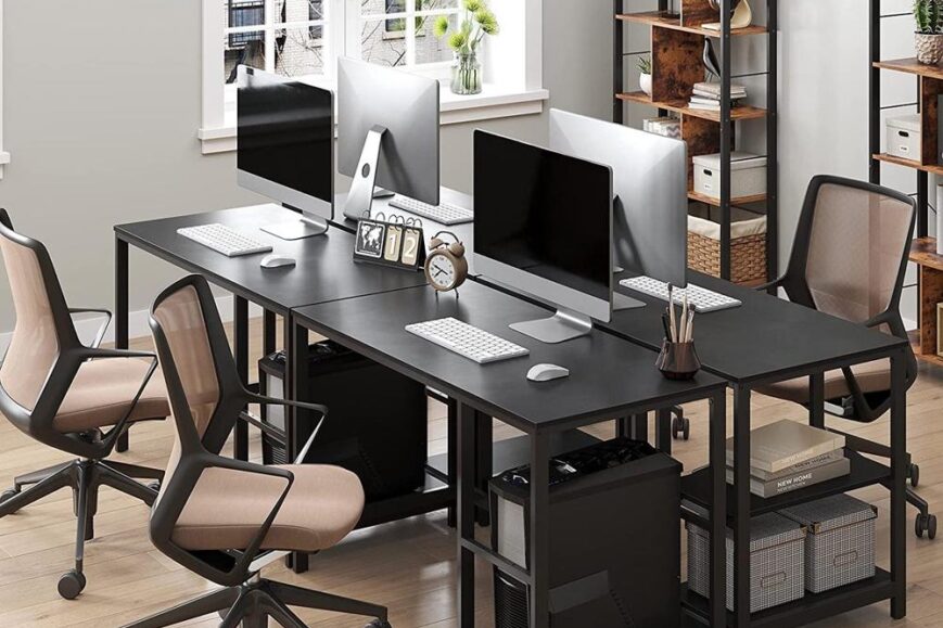 Moderne kantoortafel met twee grote computerschermen en ergonomische stoelen. De ruimte heeft lichtinval van een raam en creatieve opslagoplossingen op de achtergrond.