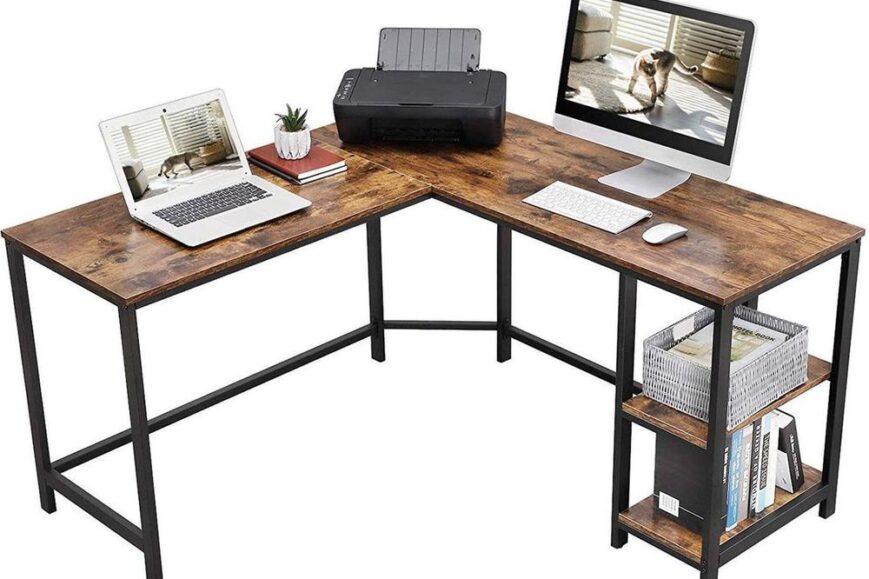 Een U-vormig bureau met een houten bovenblad en zwarte metalen poten, uitgerust met een laptop, een desktopcomputer en een printer. Onder het bureau bevinden zich planken met boeken en een opbergmandje, waardoor het een praktische werkruimte biedt.