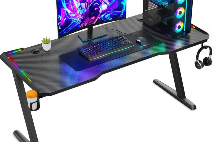 Een modern gamingbureau met een ultrawide monitor en een op maat gemaakte gaming-pc met RGB-verlichting. Het bureau is uitgerust met een toetsenbord, muismat en een plantenbakje, en heeft ook een houder voor een kopje en een set gaming-hoofdtelefoons.