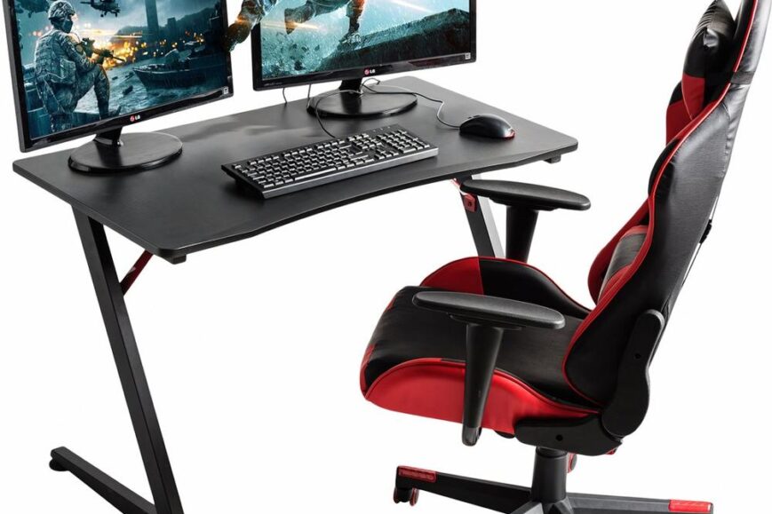 Een moderne gamingopstelling met een zwart bureau, twee monitoren die een actievolle game weergeven, en een ergonomische bureaustoel met een rode en zwarte kleurstelling. Deze afbeelding illustreert een optimale omgeving voor gamers die comfort en prestaties waarderen.