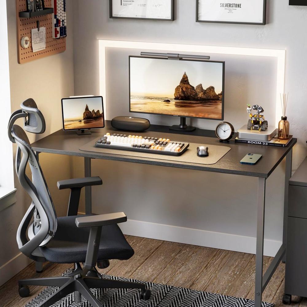 Een stijlvolle bureau-opstelling met een groot computerscherm en een tablet, verlicht door een LED-lamp achter het scherm. De ruimte is verder ingericht met een ergonomische bureaustoel, een toetsenbord, een klok en decoratieve accessoires, wat bijdraagt aan een moderne werk- of speelomgeving.