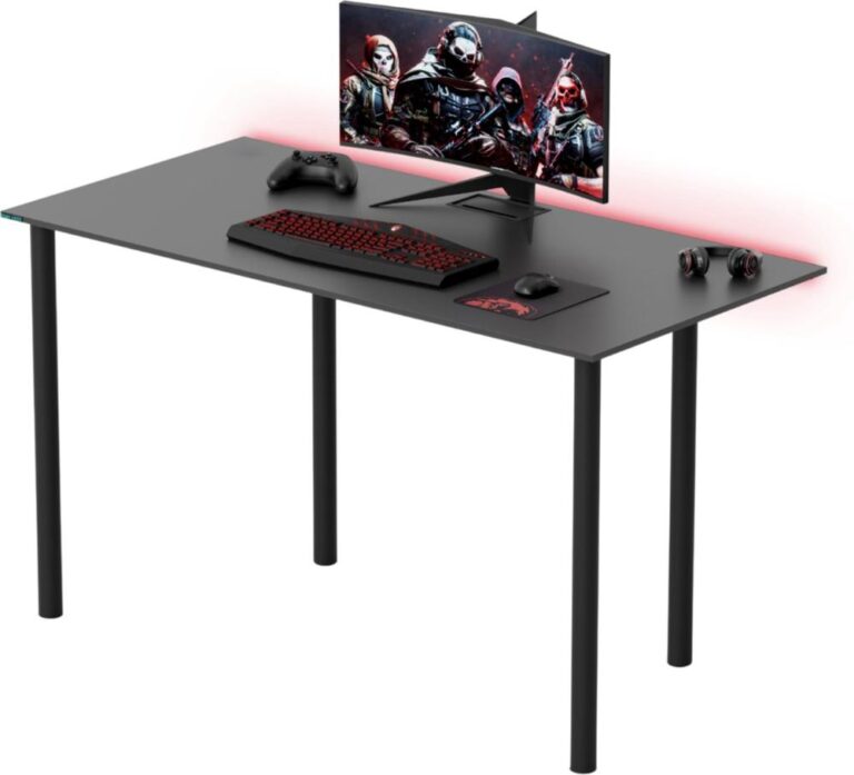 Een zwart bureau met een computer beeldscherm waarop een gaming afbeelding te zien is. Naast het scherm liggen een gaming toetsenbord, muis, een controller en een set hoofdtelefoons.