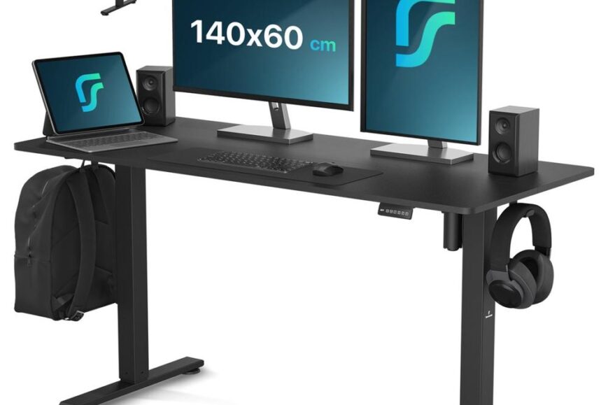 Een modern bureau met een zwart blad dat twee monitoren, een laptop, luidsprekers en een muismat bevat. Aan de zijkant van het bureau hangt een rugzak en een koptelefoon, wat een functionele en georganiseerde werkplek creëert.