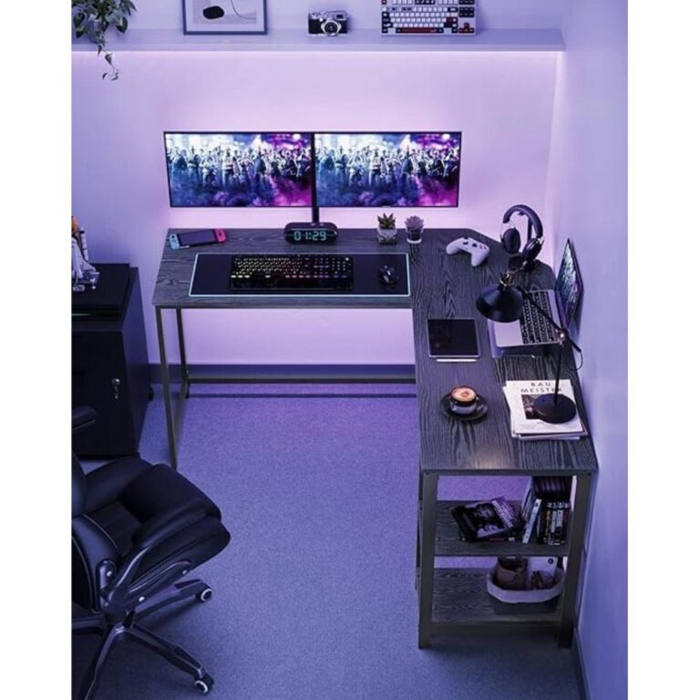 Een moderne bureautafel met twee beeldschermen, gamingaccessoires en een kleurrijk toetsenbord. De ruimte is sfeervol verlicht en bevat naast een bureaulamp ook een klok en verschillende elektronische apparaten.